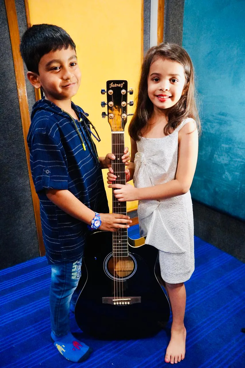 Two young academy students sharing an acoustic guitar
